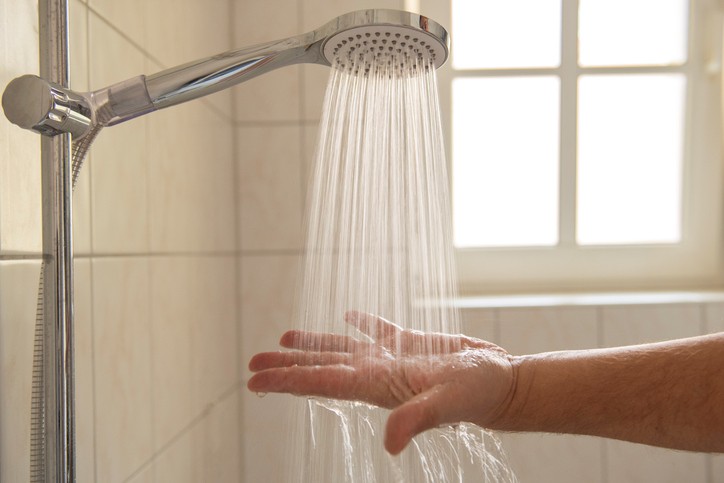 Picture of hand checking water from a shower head.